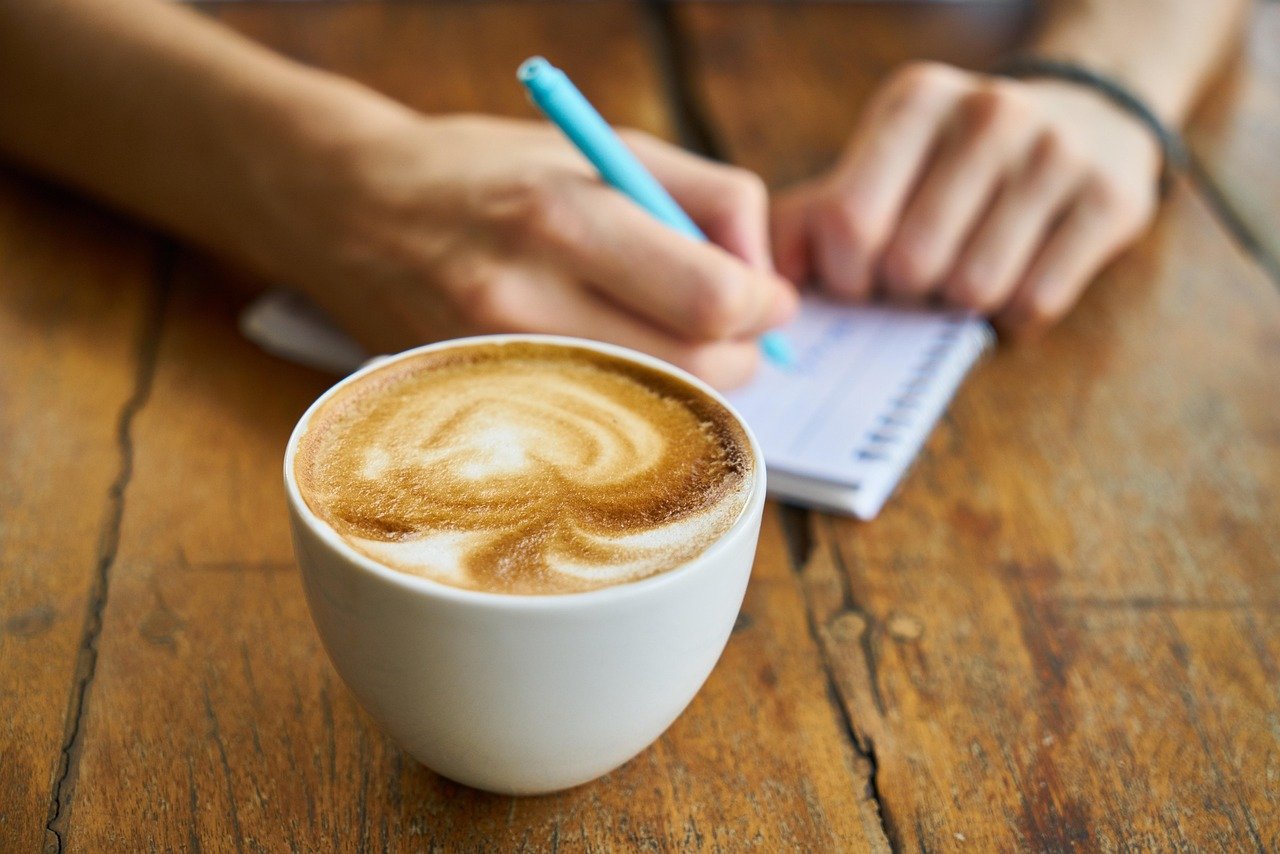 Coffee cup with person writing notes
